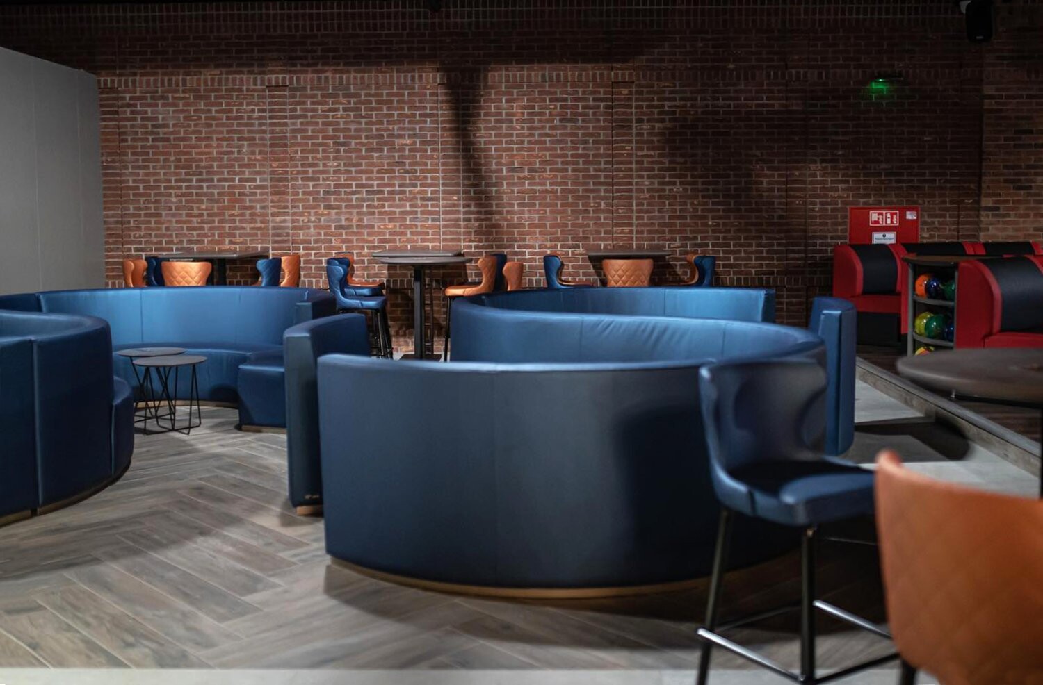 Entertainment Center Krakow - lounge with curved blue banquette seating against an exposed brick wall