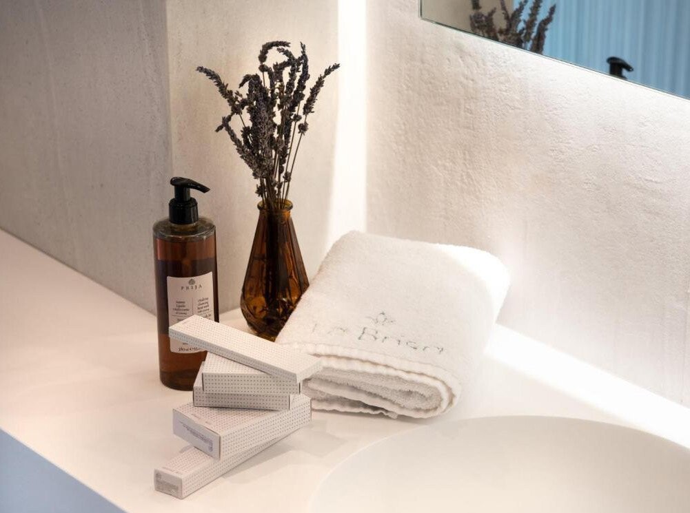 La Brisa Hotel - folded towels with a soap dispenser and dried flowers on a bathroom shelf, South Albania