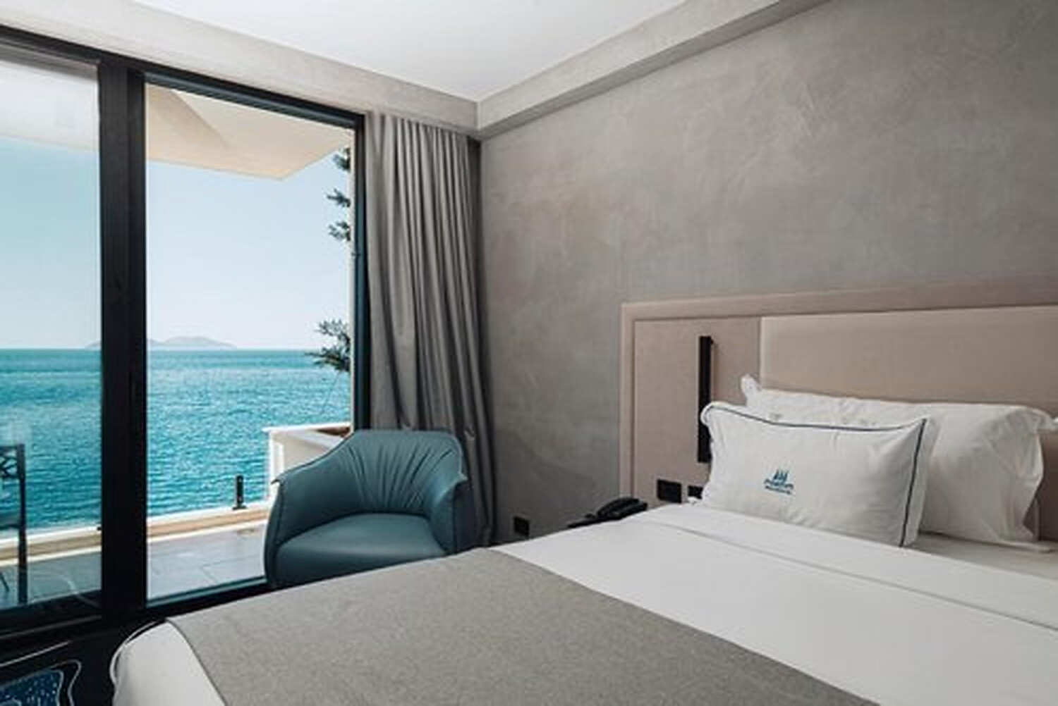 Maritim Collection Marina Bay Hotel - guest room with a teal armchair and balcony doors facing the sea, Vlora