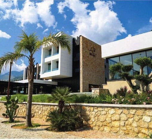 Nassau Hotel - hotel building exterior with stone walls and palm trees, South Albania